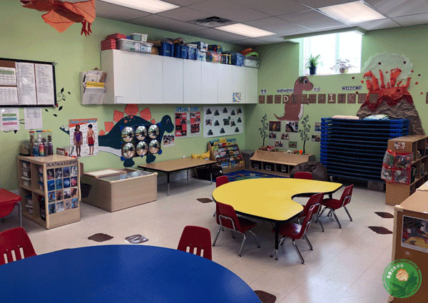 Photo of our toddler room, including a book centre and activity tables.